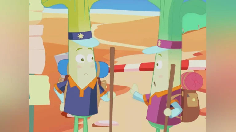 Two animated characters resembling leeks, wearing colorful hiking outfits, hats, and backpacks, stand on a sandy path discussing. One carries a yellow sign. The background shows a desert landscape with striped barriers and distant cliffs.